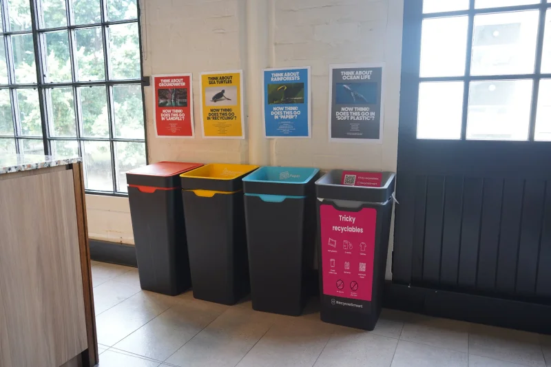 Colour-coded recycling bins lined up against an office wall