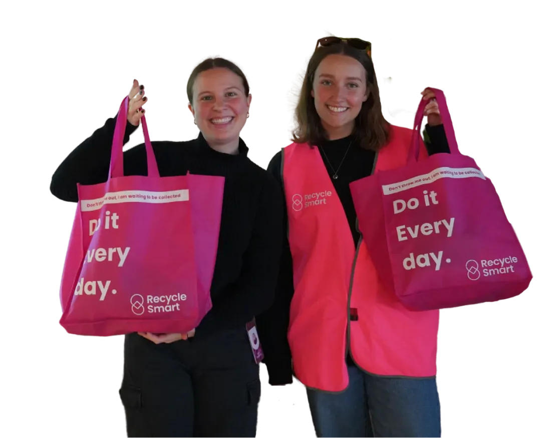 Two women in pink ReSmart vests smiling and holding pink reusable tote bags