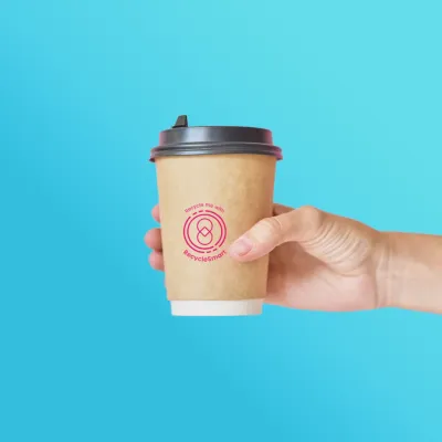 Hand holding a paper coffee cup with a pink recycling logo