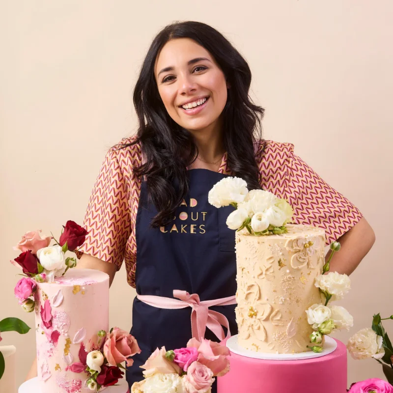Mad About Cakes founder smiling beside decorated cakes
