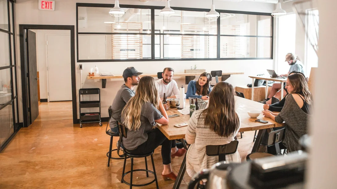 Colleagues talking around a table in a shared office