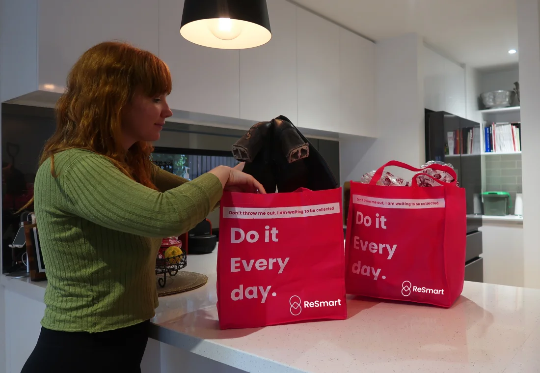 A woman filling ReSmart pickup bags on a kitchen bench