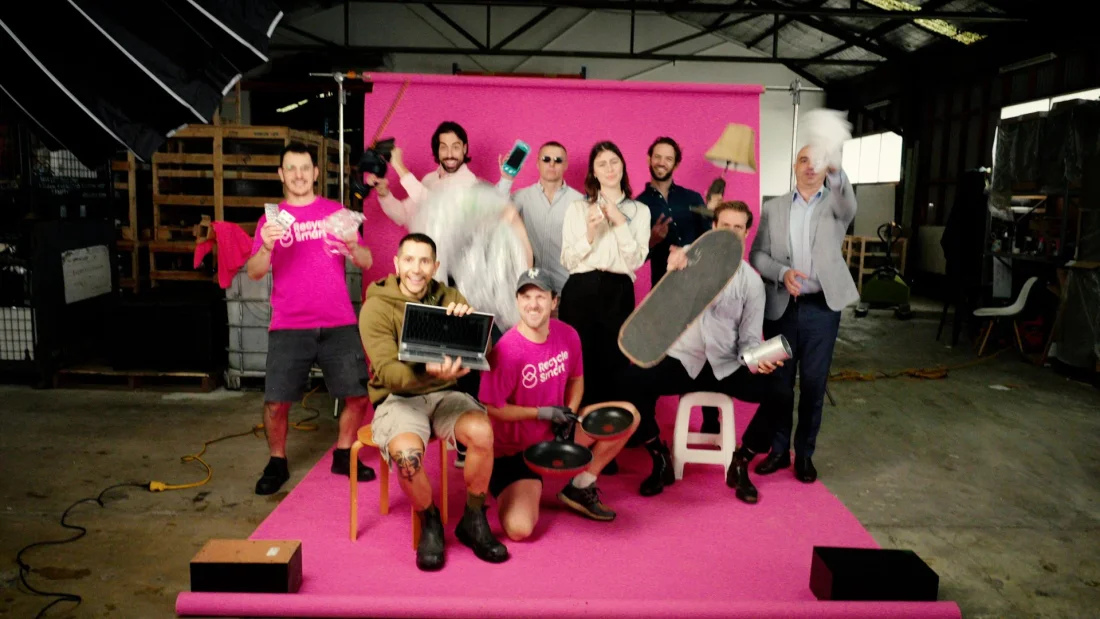 The ReSmart team posing together with recycled items in front of a pink wall