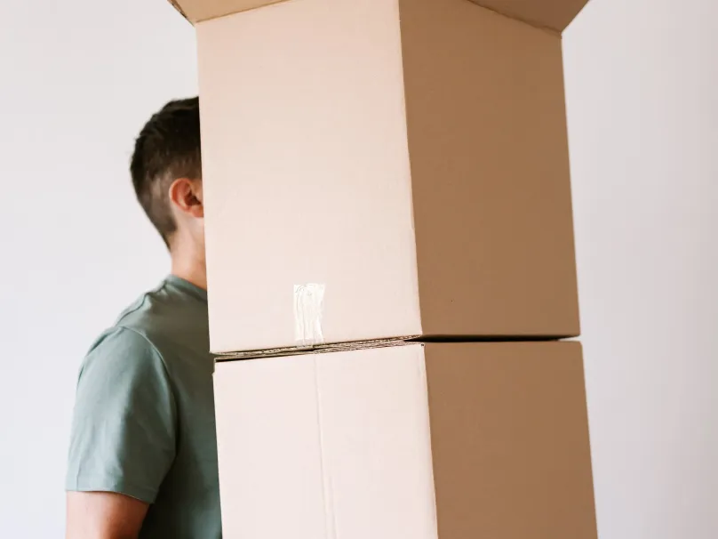 A man carrying two large stacked cardboard boxes