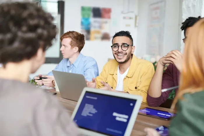 Smiling colleagues working together on laptops around a table