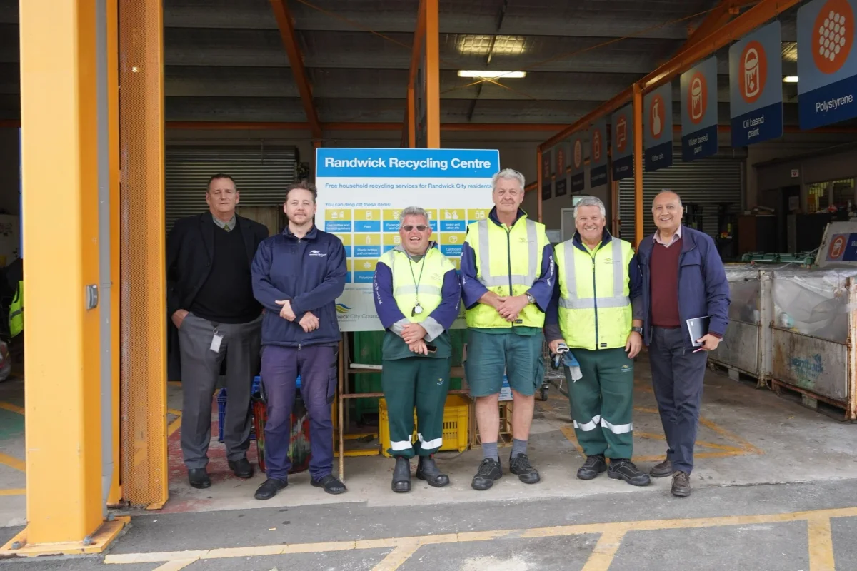 Staff standing in front of the Randwick Recycling Centre sign