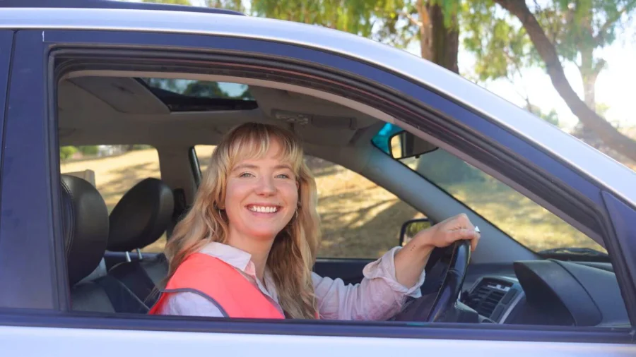 Smiling ReSmart driver in a pink vest behind the wheel of a car