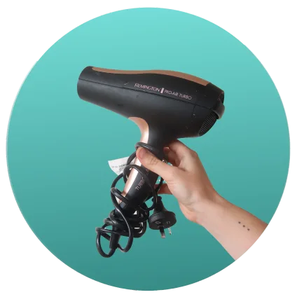 Hand holding a black and gold hair dryer
