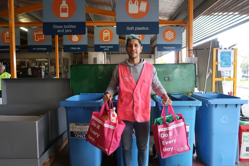 ReSmart team member holding pink bags in front of sorting bins