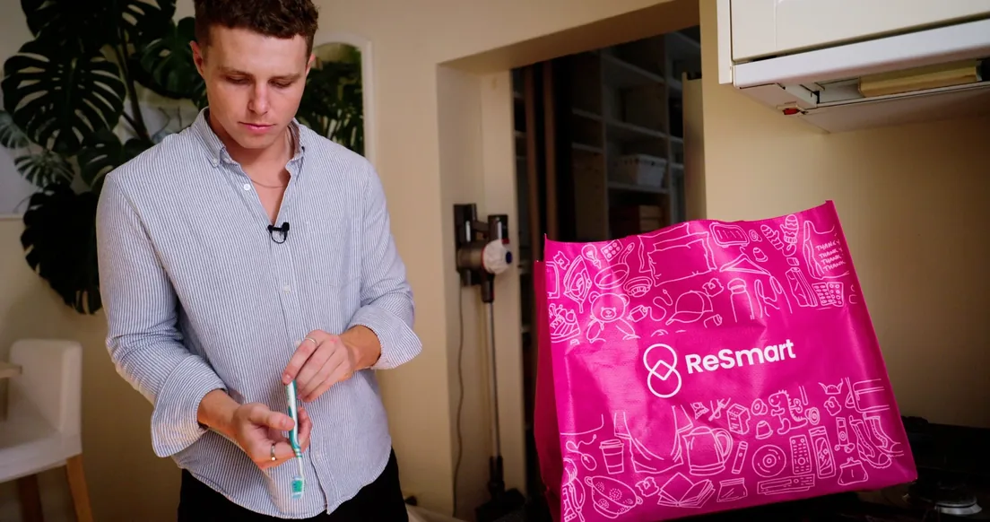 Man holding a toothbrush beside a pink ReSmart bag