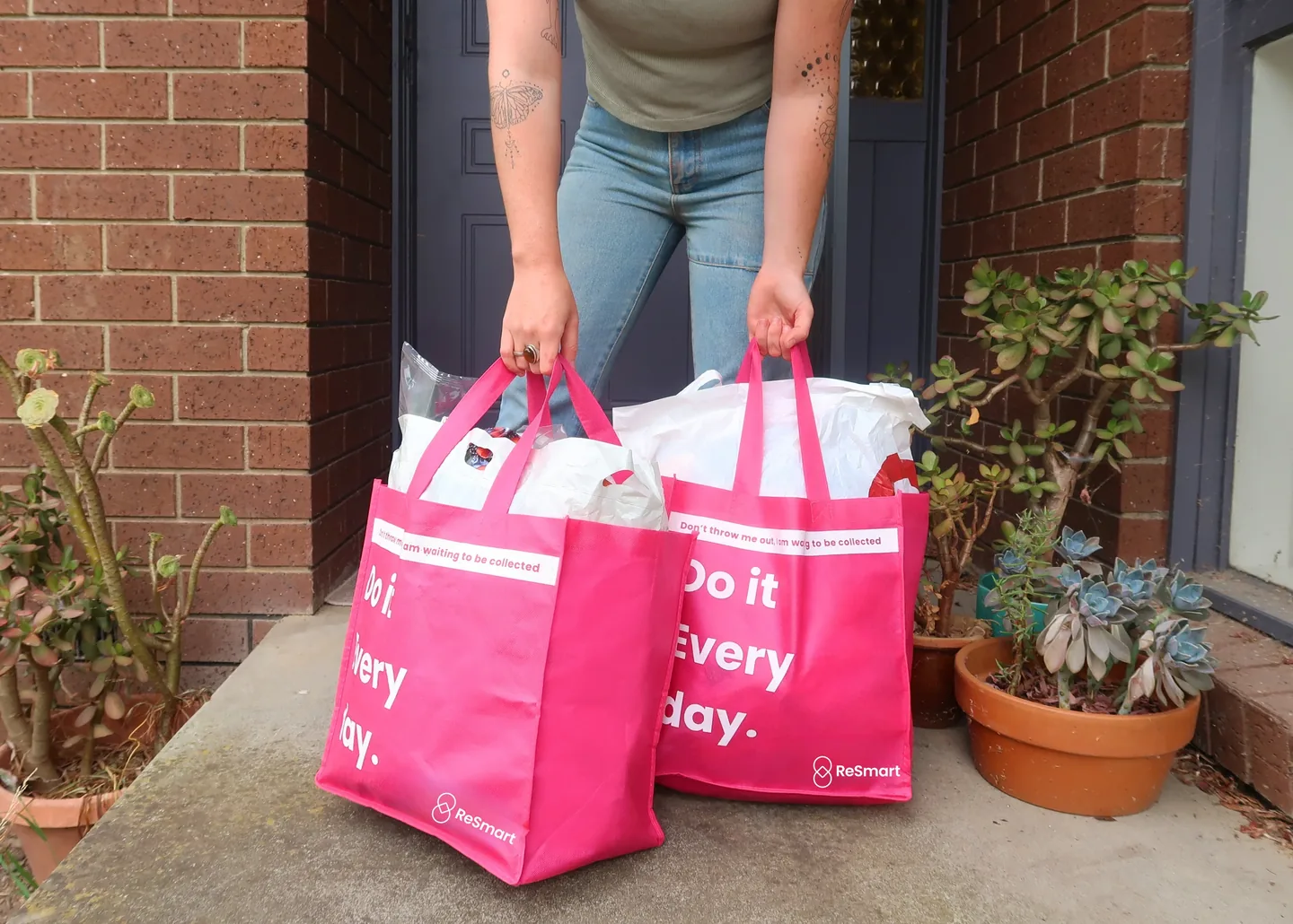Person placing two full pink ReSmart bags on a doorstep