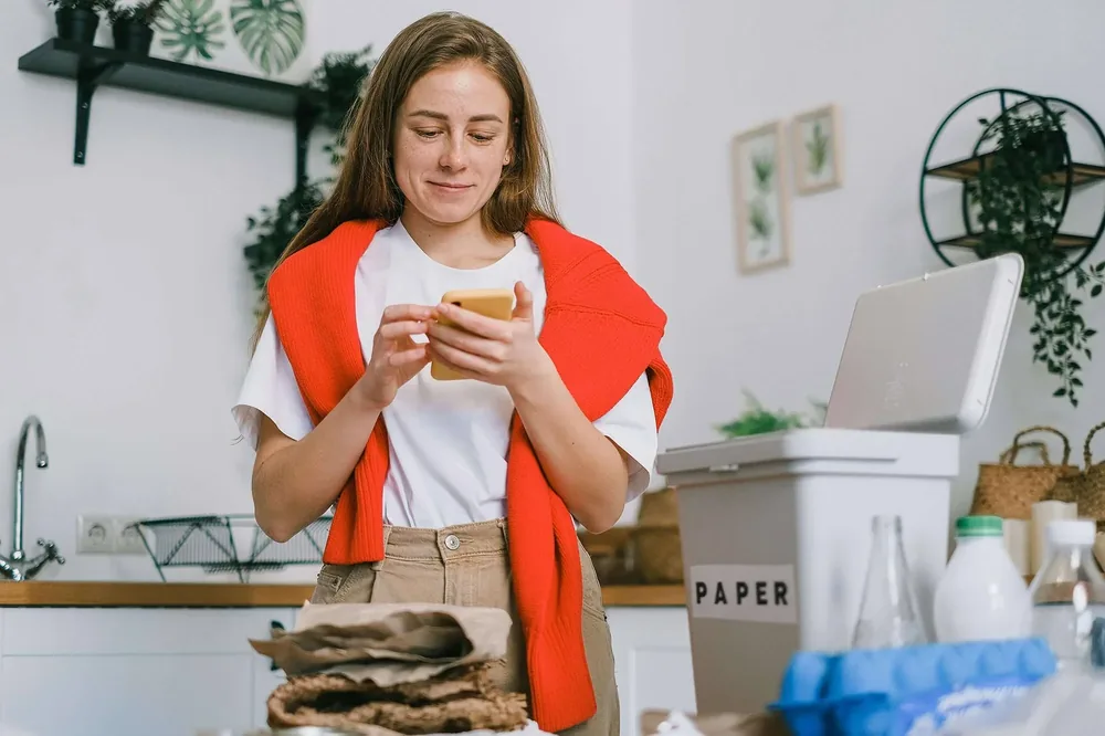 Woman in an orange jumper checking her phone