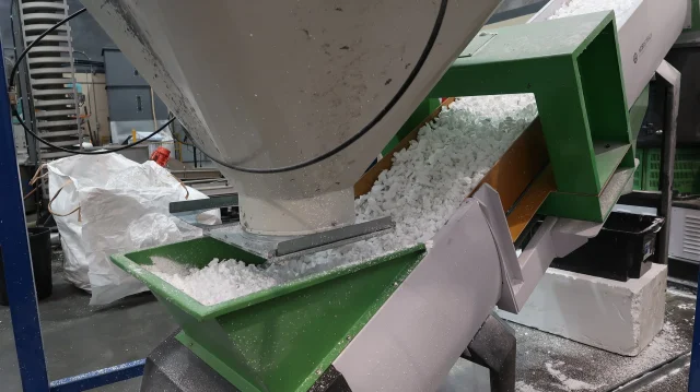 Shredded polystyrene pouring from a recycling machine