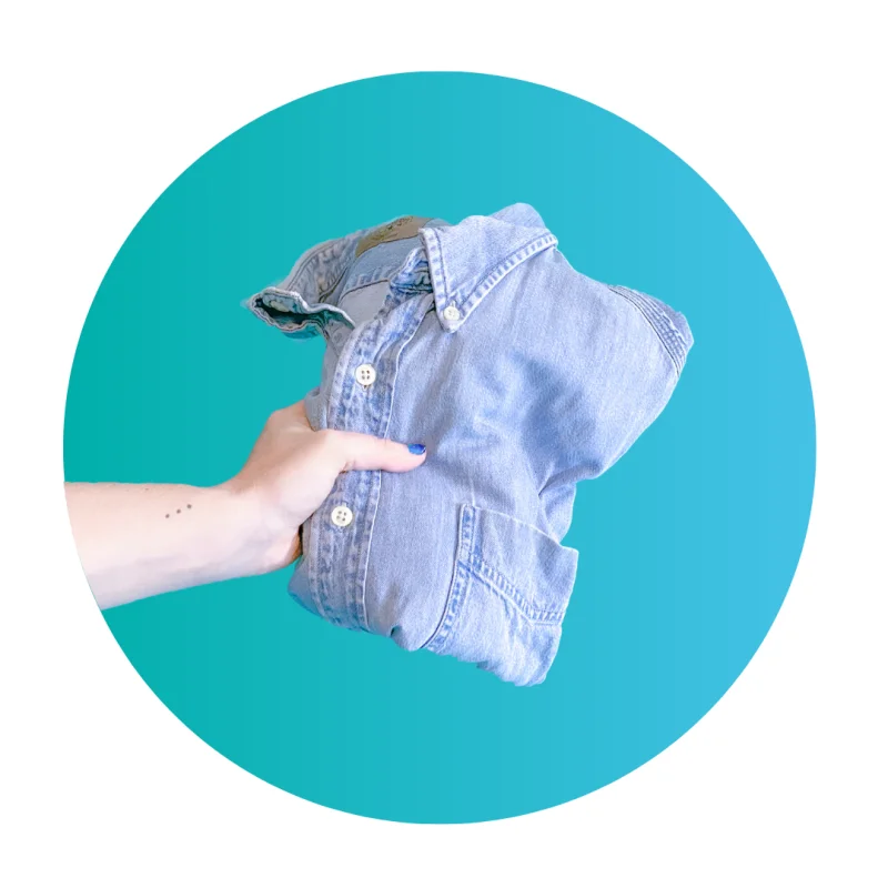 Hand holding a folded denim shirt